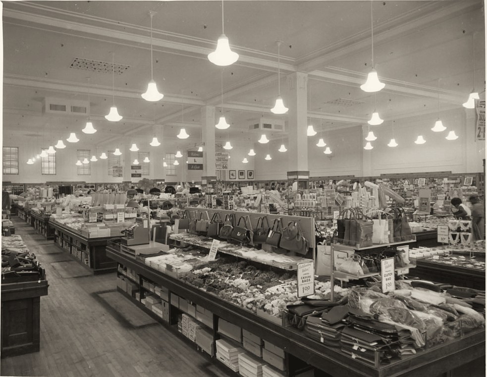 The Kress sales floor under rows of pendant lights, with counters of handbags and goods